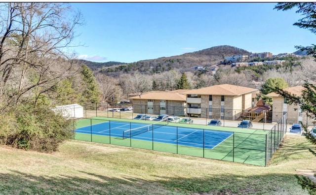 view of tennis court featuring a yard and a mountain view