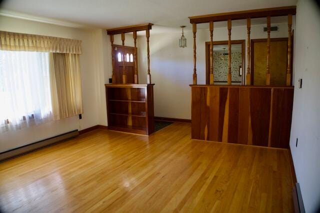 empty room with hardwood / wood-style flooring and baseboard heating