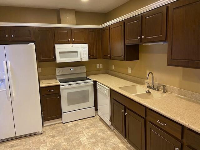 kitchen with dark brown cabinets, sink, and white appliances