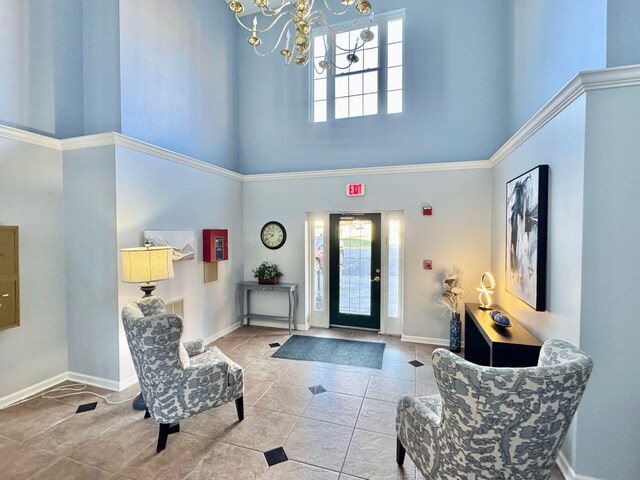 entryway with ornamental molding, a towering ceiling, a notable chandelier, and tile patterned floors