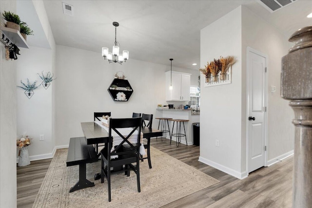 dining room featuring wood-type flooring and an inviting chandelier