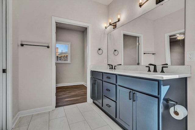 bathroom with tile patterned flooring, a sink, baseboards, and double vanity