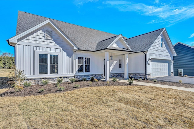 modern farmhouse featuring aphalt driveway, an attached garage, roof with shingles, board and batten siding, and a front yard