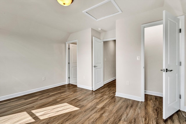 unfurnished bedroom featuring attic access, baseboards, and wood finished floors