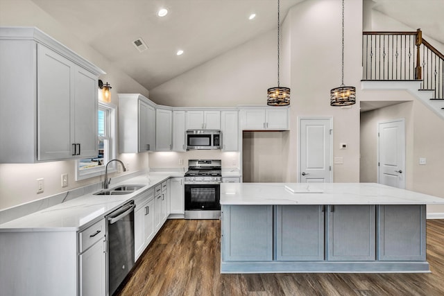 kitchen featuring a center island, dark wood-style flooring, stainless steel appliances, white cabinetry, and a sink