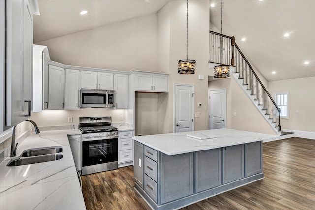 kitchen featuring dark wood finished floors, a kitchen island, appliances with stainless steel finishes, gray cabinets, and a sink