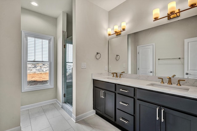 bathroom featuring double vanity, an enclosed shower, baseboards, and a sink