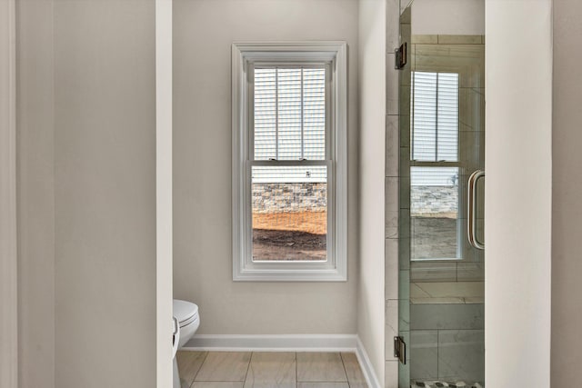 bathroom with a shower stall, a wealth of natural light, and baseboards