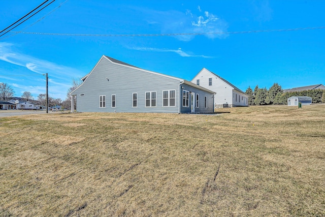 rear view of property featuring a lawn and an outdoor structure