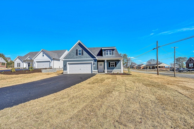 view of front of house with a porch, a garage, driveway, a residential view, and a front yard