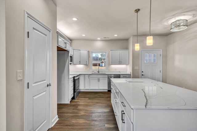 kitchen with light stone counters, dark wood-style floors, pendant lighting, recessed lighting, and appliances with stainless steel finishes