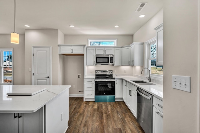 kitchen with light stone counters, dark wood-style floors, visible vents, appliances with stainless steel finishes, and a sink