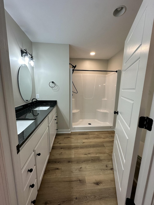 bathroom with hardwood / wood-style flooring, vanity, and walk in shower