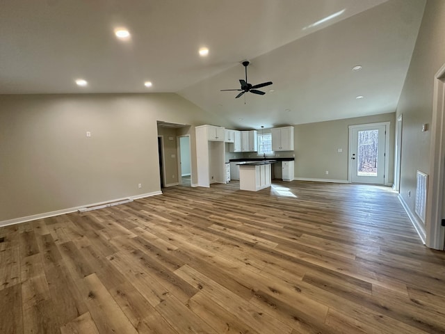 unfurnished living room with vaulted ceiling, light hardwood / wood-style floors, and ceiling fan