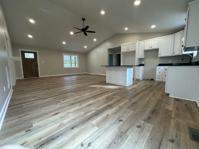 kitchen with a center island, vaulted ceiling, light hardwood / wood-style flooring, ceiling fan, and white cabinets