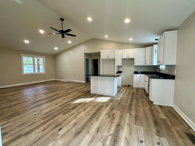 kitchen with light wood-type flooring, a kitchen island, and white cabinets