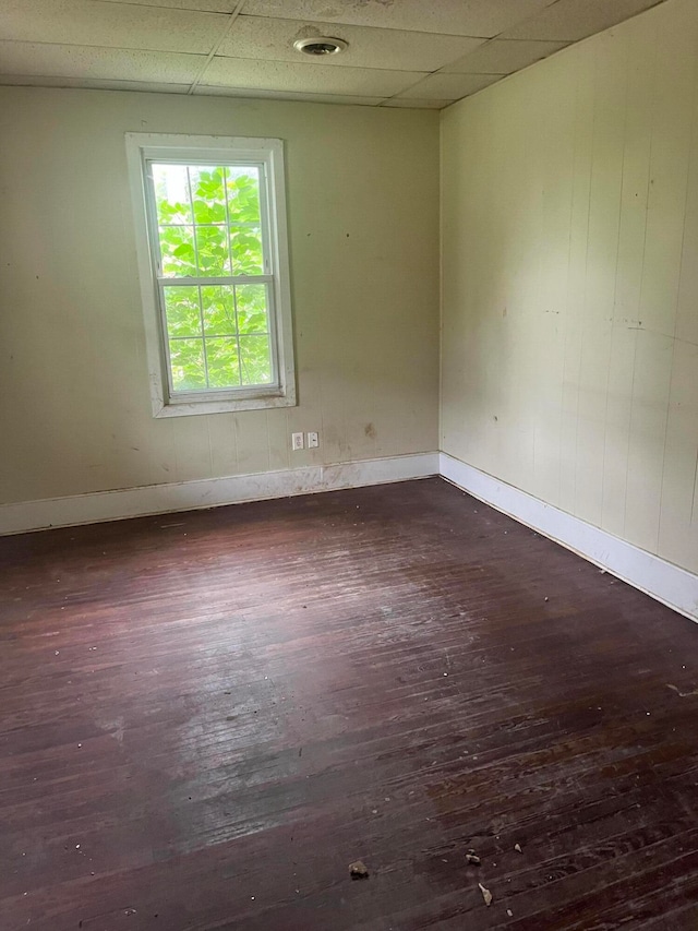 empty room with a paneled ceiling and dark hardwood / wood-style flooring