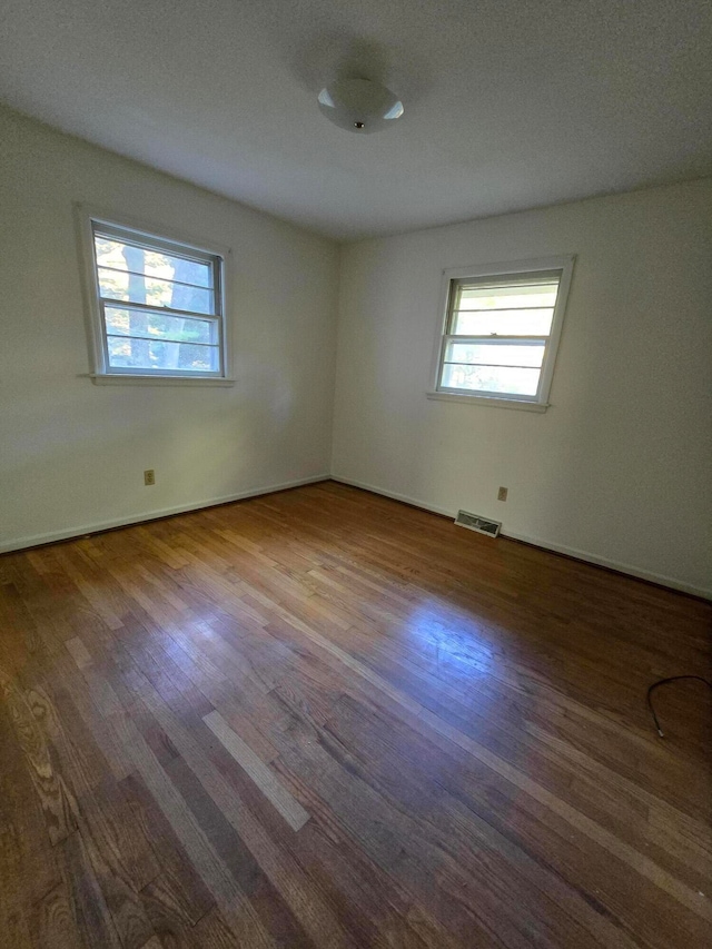 unfurnished room with hardwood / wood-style flooring and a textured ceiling