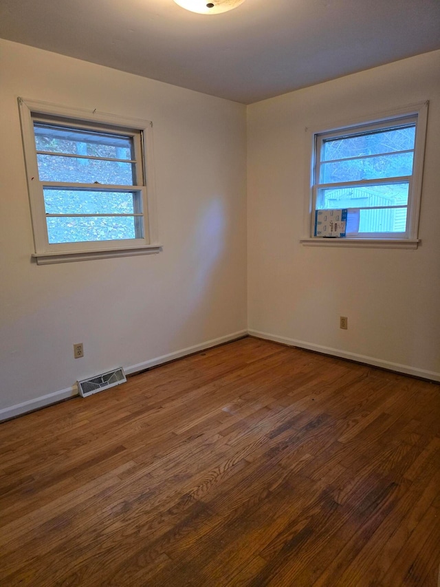 unfurnished room with dark wood-type flooring and a wealth of natural light