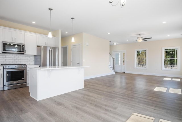 6913 Doral Dr, Radford, VA 24141 - kitchen with stainless steel appliances, open floor plan, decorative backsplash, light countertops, and a kitchen island