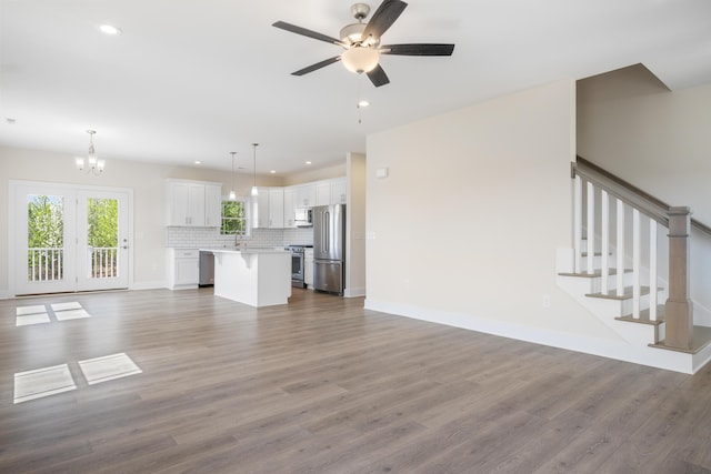 6913 Doral Dr, Radford, VA 24141 - unfurnished living room with recessed lighting, stairway, wood finished floors, baseboards, and ceiling fan with notable chandelier