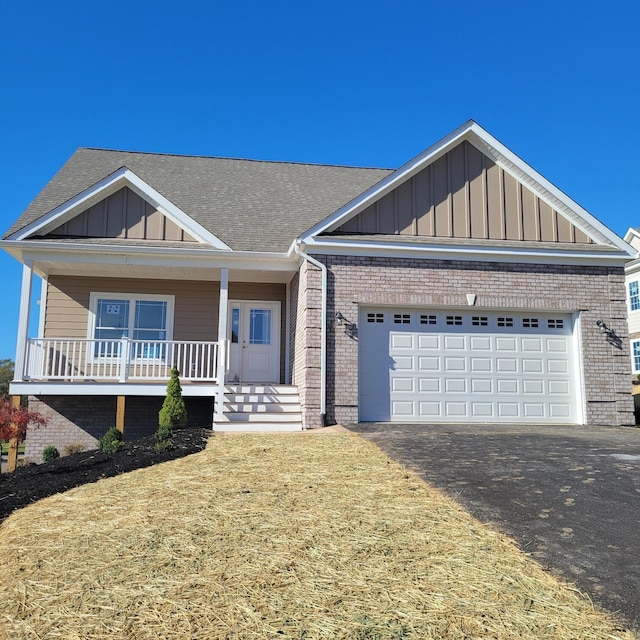 view of front of home with a front yard, covered porch, and a garage