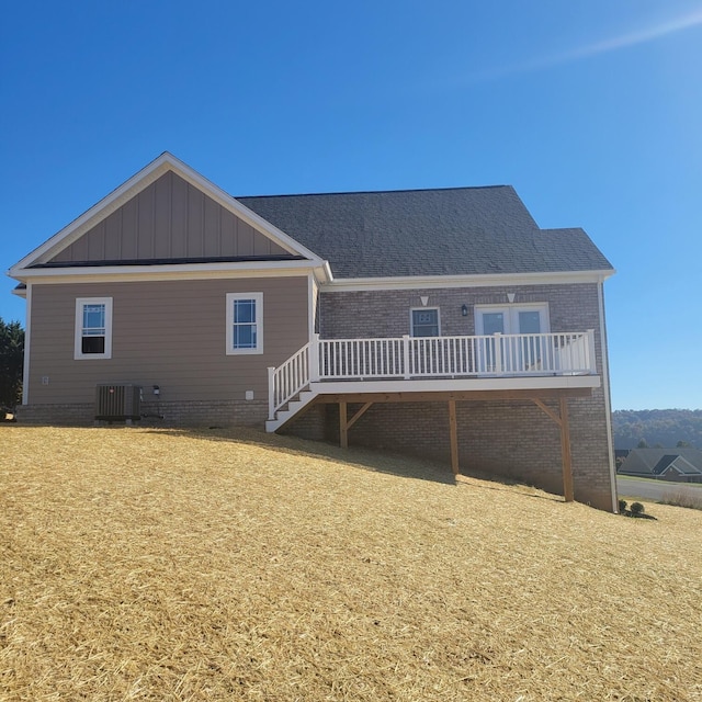 rear view of property featuring a wooden deck, a lawn, and central AC unit