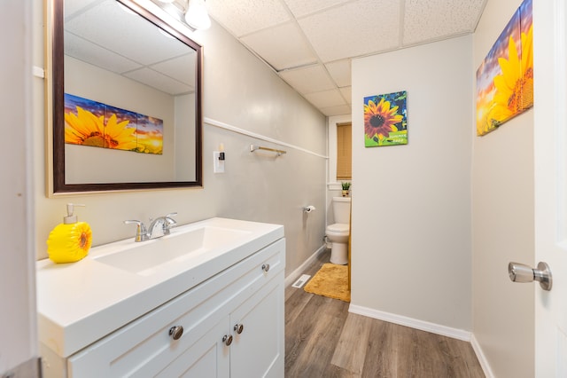 bathroom featuring vanity, toilet, wood-type flooring, and a paneled ceiling