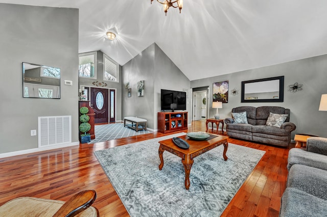 living room with a notable chandelier, high vaulted ceiling, and hardwood / wood-style flooring