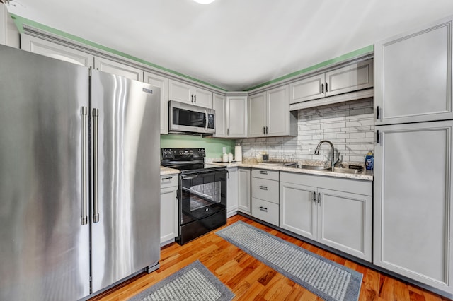 kitchen featuring light stone countertops, light hardwood / wood-style floors, appliances with stainless steel finishes, and sink