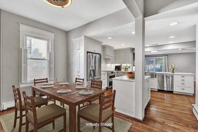 dining room featuring ceiling fan, sink, baseboard heating, and dark hardwood / wood-style flooring