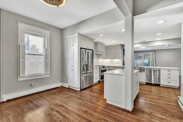 kitchen with stainless steel appliances, a baseboard heating unit, dark hardwood / wood-style floors, and white cabinets