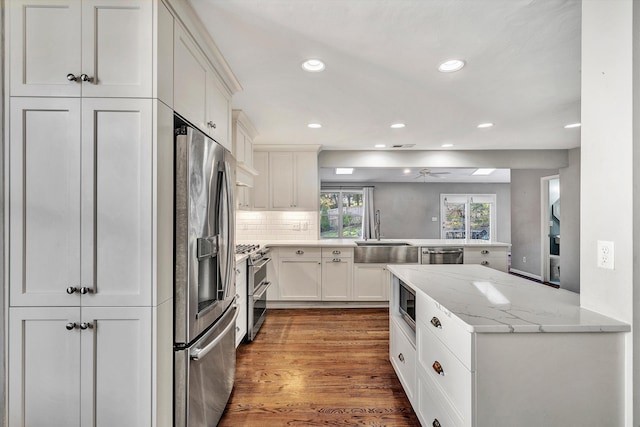 kitchen featuring white cabinetry, light stone counters, stainless steel appliances, and kitchen peninsula