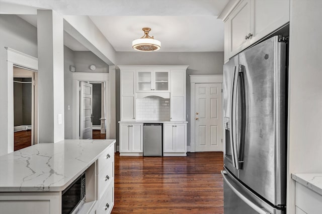 kitchen featuring white cabinets, stainless steel fridge with ice dispenser, built in microwave, dark wood-type flooring, and light stone counters