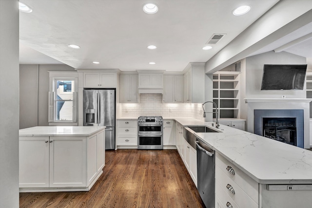 kitchen with light stone countertops, appliances with stainless steel finishes, sink, dark hardwood / wood-style flooring, and white cabinets