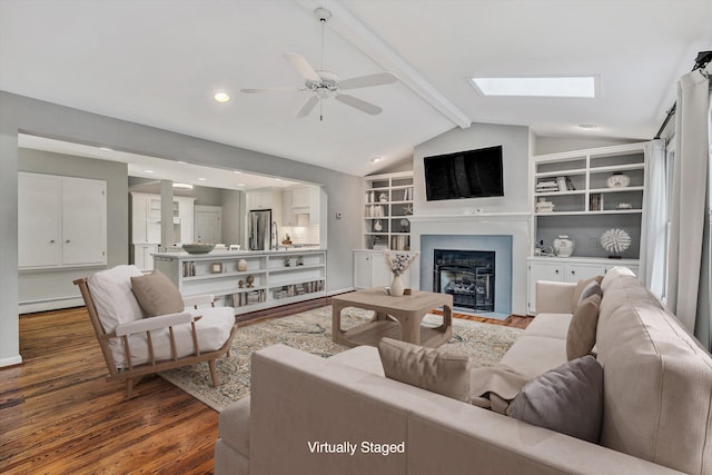 living room with ceiling fan, dark hardwood / wood-style flooring, built in shelves, lofted ceiling with skylight, and baseboard heating