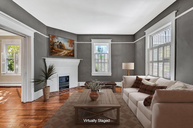 living room featuring a wealth of natural light, a brick fireplace, and dark hardwood / wood-style floors