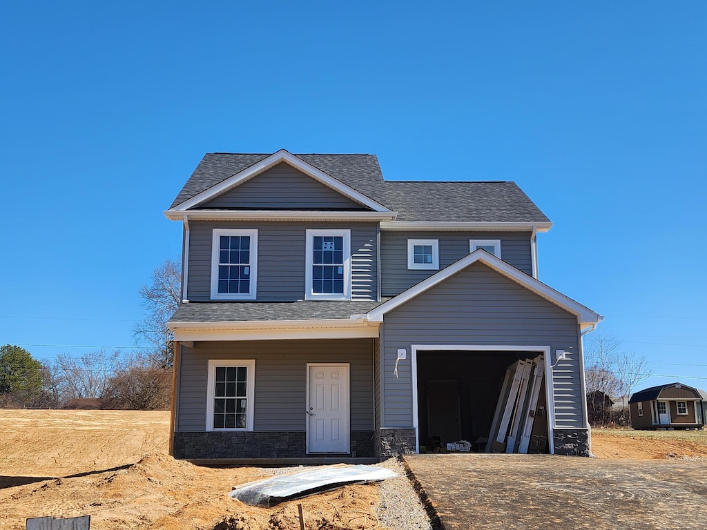 view of front of home featuring stone siding and roof with shingles