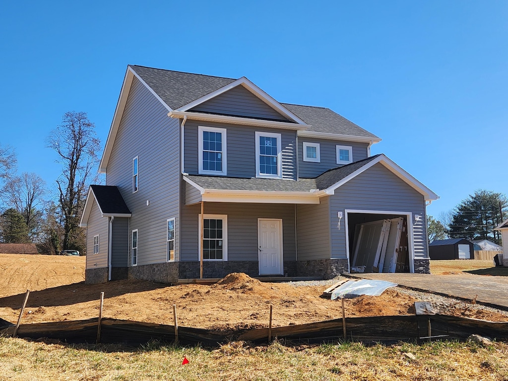 view of front of home featuring a garage, stone siding, and a shingled roof