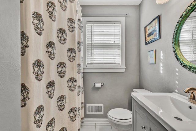 bathroom with tile patterned floors, a wealth of natural light, vanity, and toilet