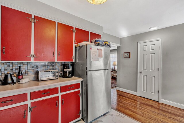 kitchen featuring stainless steel fridge, backsplash, and light hardwood / wood-style flooring