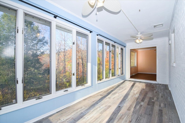 unfurnished sunroom featuring ceiling fan and plenty of natural light