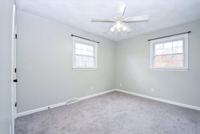 carpeted spare room featuring a healthy amount of sunlight and ceiling fan