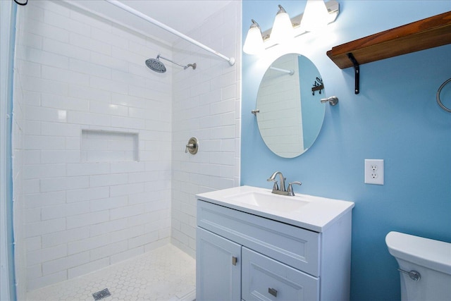 bathroom with vanity, a tile shower, and toilet