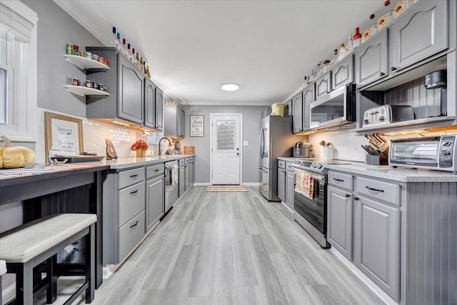 kitchen with appliances with stainless steel finishes, light wood-type flooring, gray cabinets, and tasteful backsplash