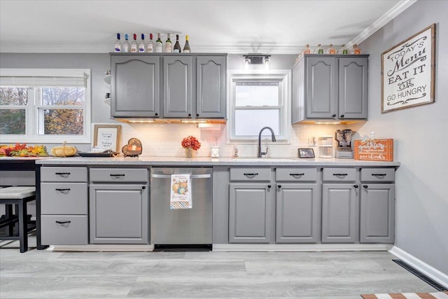 kitchen featuring sink, tasteful backsplash, light hardwood / wood-style flooring, stainless steel dishwasher, and ornamental molding