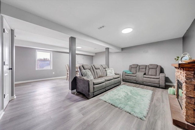 living room with a stone fireplace and light hardwood / wood-style floors