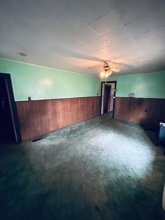 spare room featuring carpet flooring, ceiling fan, and wood walls