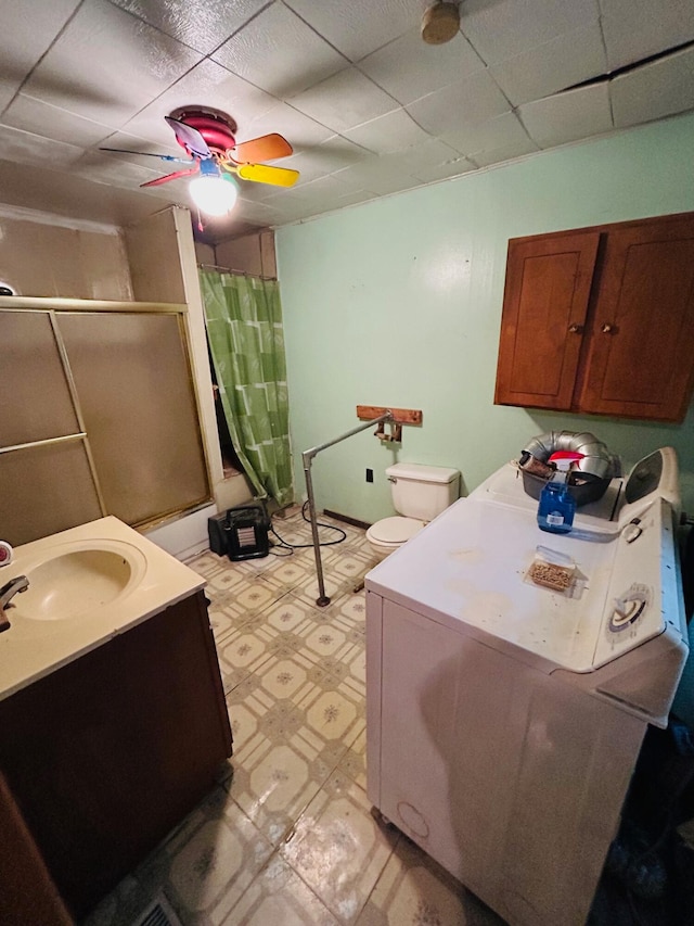 bathroom with vanity, a shower with shower curtain, ceiling fan, toilet, and washer / clothes dryer