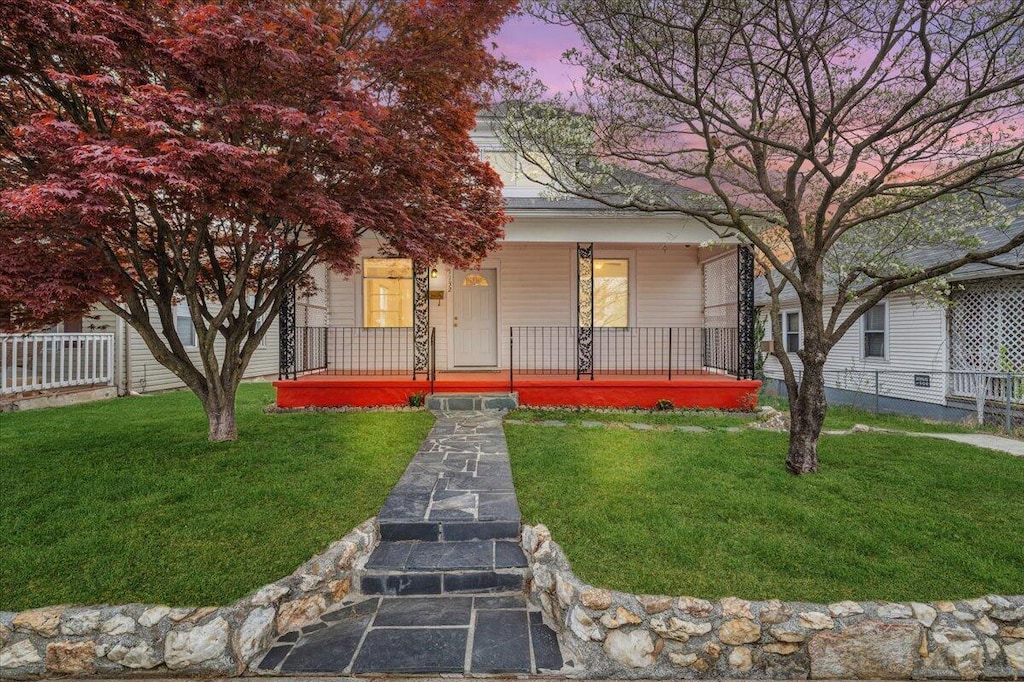 view of front of home with a porch, fence, and a yard